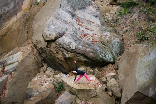 Preview: Sporty fit woman is practicing yoga on the boulder in the nature