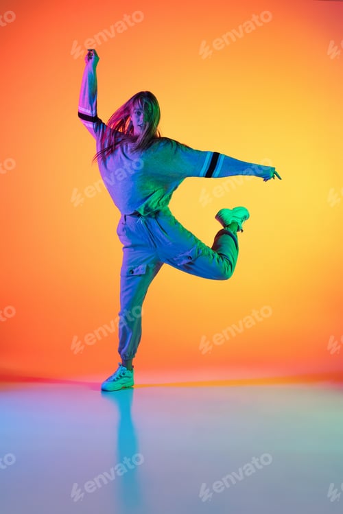 Preview: Portrait of young sportive girl dancing hip-hop in stylish clothes on colorful background at dance