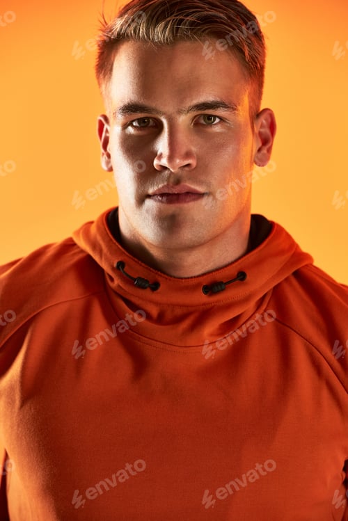 Preview: Studio portrait of a handsome young male athlete posing against an orange background