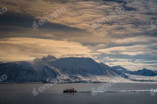 Preview: A SMALL ZODIAC MOTORING IN FRONT OF A SNOW COVERED MOUNTAIN RANGE NEAR SVALBARD NORAY
