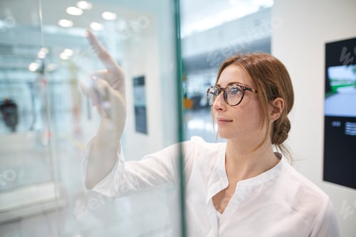 Preview: Young businesswoman touching virtual touchscreen