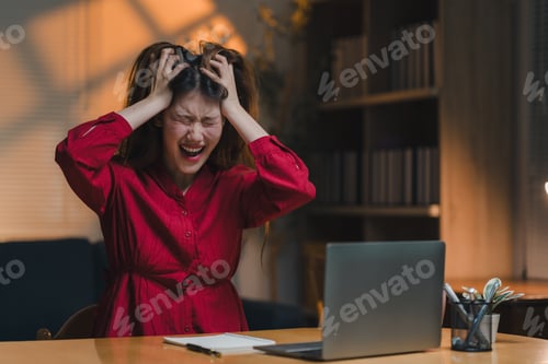 Preview: Stressed asian freelancer screaming while working at home office desk