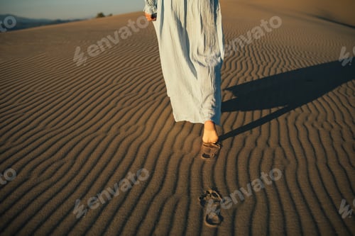 Preview: Close-up of a woman's bare feet leaving footprints on the sand.