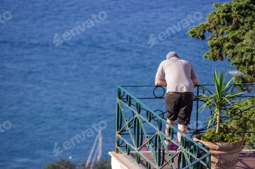 Preview: Beautiful shot of a man looking from a balcony at the sea in Capri Island, Italy