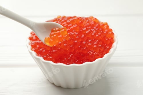 Preview: Taking tasty red caviar with spoon from bowl on white wooden table, closeup