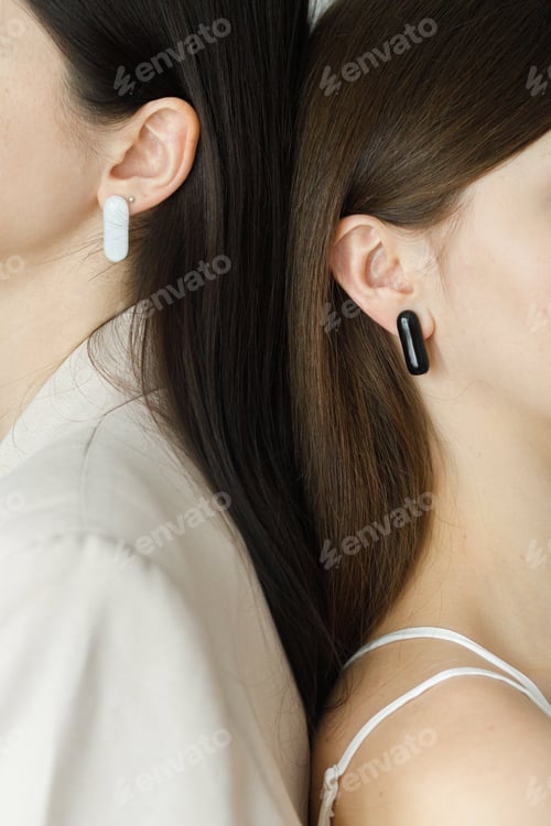 Preview: Two beautiful stylish women with modern geometric earrings posing together,cropped view. Beauty care