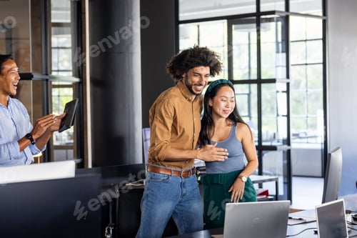 Preview: Colleagues celebrating success in modern office, smiling and embracing teamwork