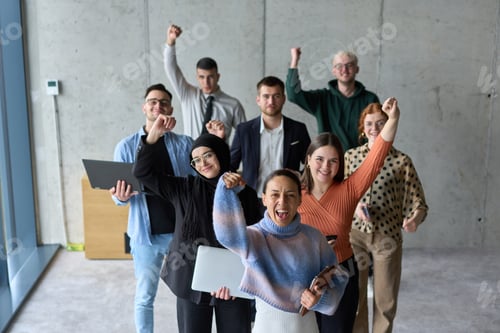 Preview: A diverse team of business professionals ecstatically celebrating their success in a modern office