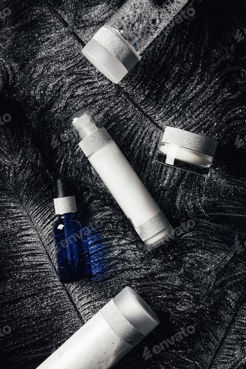Preview: elevated view of beauty cream, lotion, serum and micellar water on surface with black feathers