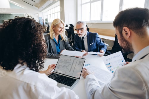 Preview: Businesspeople analyzing financial charts and reports in office meeting using laptop, working