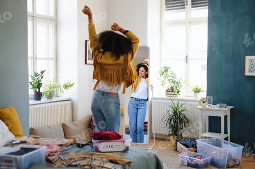 Preview: Rear view of young woman sorting wardrobe indoors at home, charity donation concept.