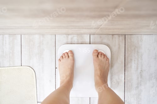 Preview: Female adult weighing on digital scale in bathroom for weight management and health tracking