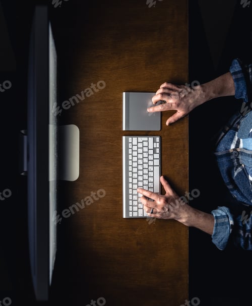 Preview: A man works in front of a computer at night, top view.