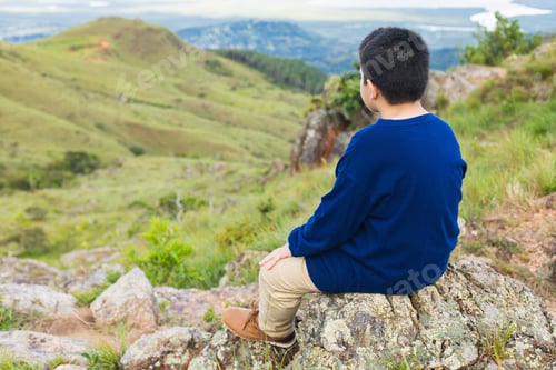 Preview: boy sitting on the rock looking at the landscape