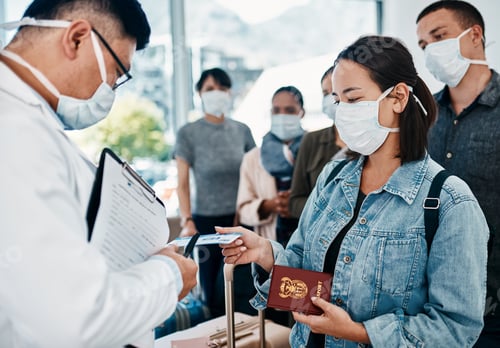 Preview: Shot of a woman wearing a mask and giving her passport to a doctor in an airport