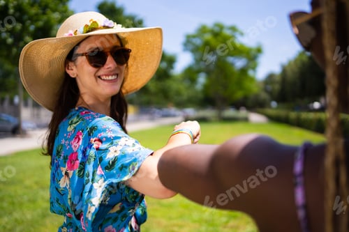 Preview: Selective focus on a woman in hat waving with the elbow to an african woman