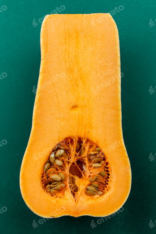 Preview: Ripe orange pumpkin cut in half on a green surface