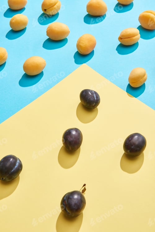 Preview: close-up view of fresh sweet plums and apricots on blue and yellow background
