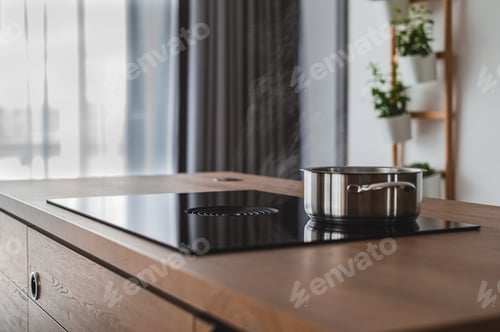 Preview: Beautiful interior shot of shiny modern cooker with a metal pot in the kitchen with a wooden surface