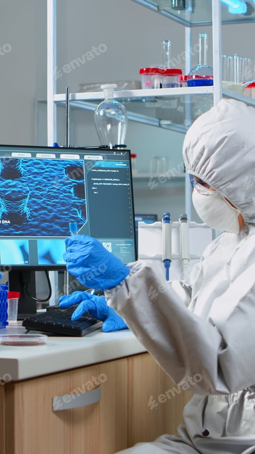 Preview: Chemist with coverall looking at virus test in equipped lab