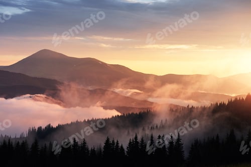 Preview: Beautiful sunset in the mountains. Landscape with sun light shining through orange clouds and fog
