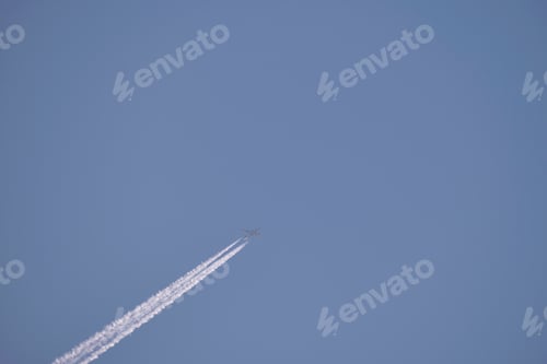 Preview: Distant passenger jet plane flying on high altitude on clear blue sky leaving white smoke