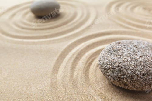 Preview: Rocks create patterns in sand during a sunny day at a beachside location