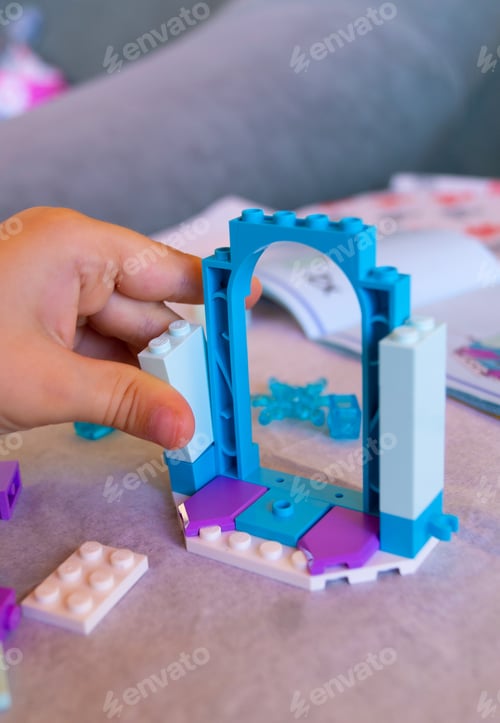 Preview: Kid playing Lego. Hand building up Lego Frozen series blocks, close up