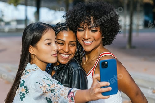Preview: Female friends sharing a joyful selfie moment in an urban setting at dusk.