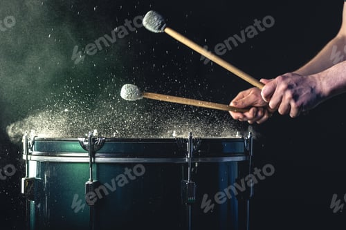 Preview: A man plays a musical percussion instrument with sticks on a dark background.
