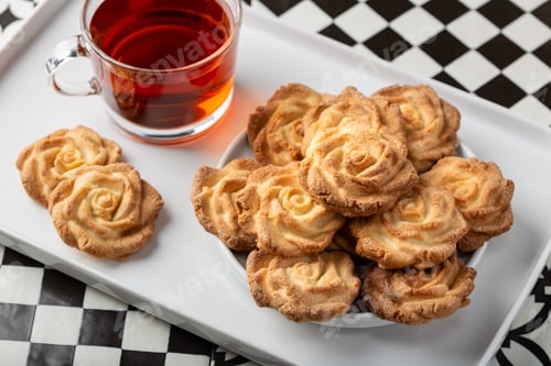Preview: Homemade rose-shaped shortbread cookies served with tea on a white tray