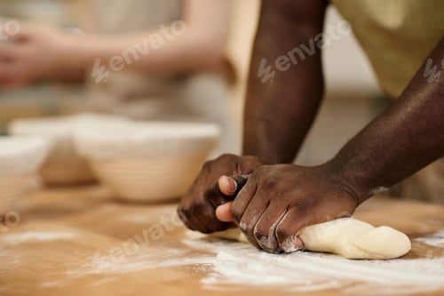 Preview: Close up of Black man kneading dough for fresh bread in bakery
