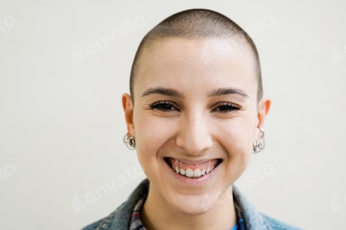 Preview: Happy bald young woman smiling on camera outdoors - Diversity, androgynous concept - Focus on face