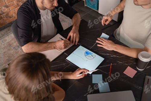 Preview: Team collaboration using a tablet in a modern workspace setting.