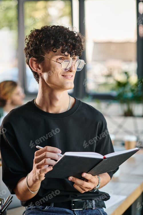 Preview: Curly-haired startup team member with glasses smiling and taking notes in a dynamic office space