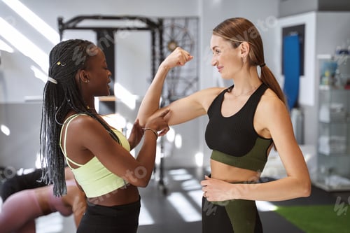 Preview: Woman showing her muscles to her trainer after exercising at the gym.