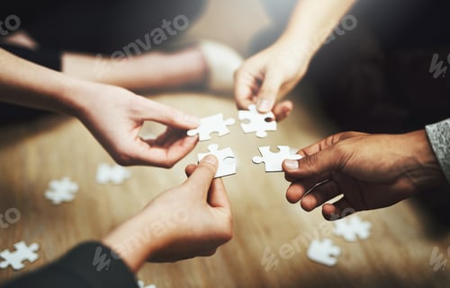 Preview: Cropped shot of a group of unrecognizable people fitting puzzle pieces together on the floor