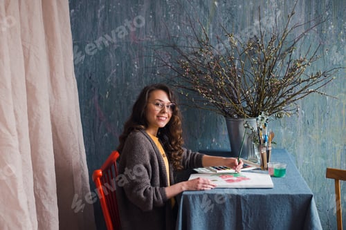 Preview: Young woman designer or artist freelancer sitting at studio workplace with watercolor sketch