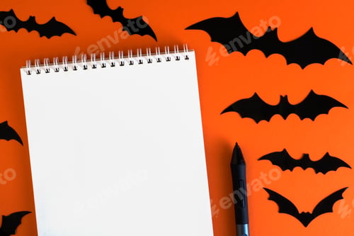 Preview: Blank notepad on orange background with paper bats silhouettes, traditional Halloween decor.