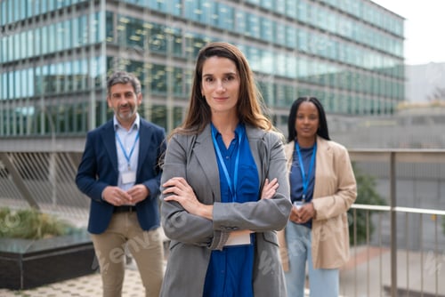 Preview: A business team with its confident leader stands outside a modern office building