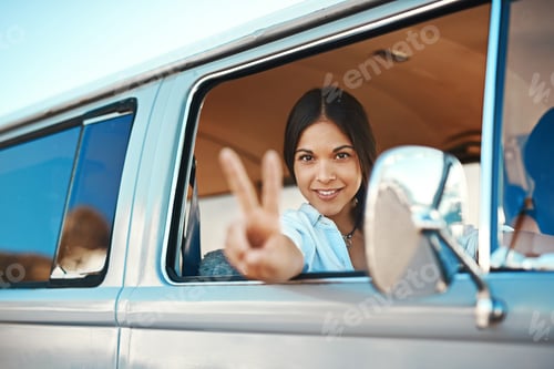 Preview: Shot of a young woman leaning out of a vans window and showing a peace sign on a roadtrip