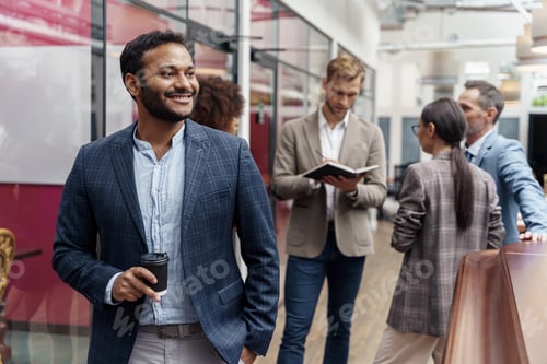 Preview: Portrait of indian businessman standing in modern office on colleagues background