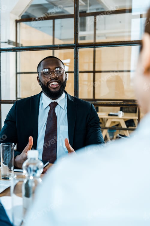 Preview: selective focus of cheerful african american man in eye glasses looking at coworker