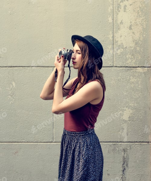 Preview: Woman Photographs with Vintage Camera Outdoors Against Wall
