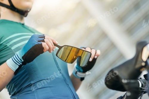 Preview: Close up of hands of professional female cyclist holding and putting on protective glasses while