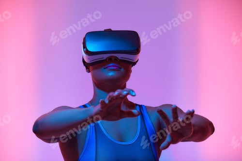 Preview: African american woman streamer playing video game using virtual reality glasses at gaming room