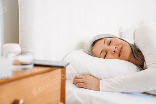 Preview: Grey asian woman sleeping while lying in bed at home