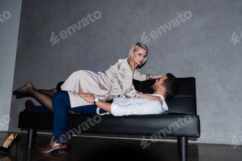 Preview: beautiful young couple lying on couch in foreplay, girl looking at camera