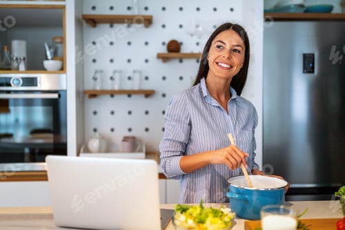 Preview: Woman smiling in kitchen with laptop and glass of milk