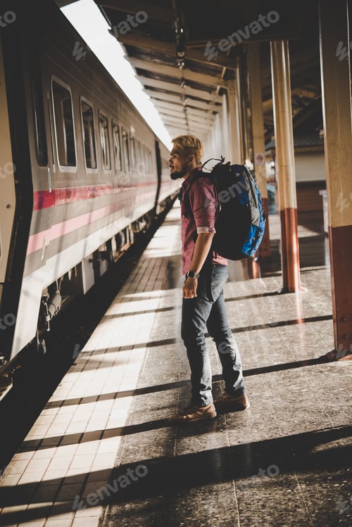 Preview: Young hipster tourist with backpack on the train station. Holiday tourist concept.